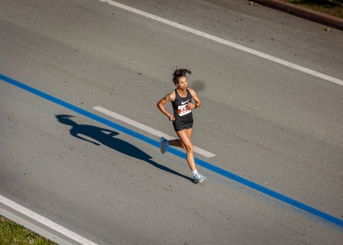 Aerial view of a woman running in a marathon on a city street, capturing endurance and athleticism.